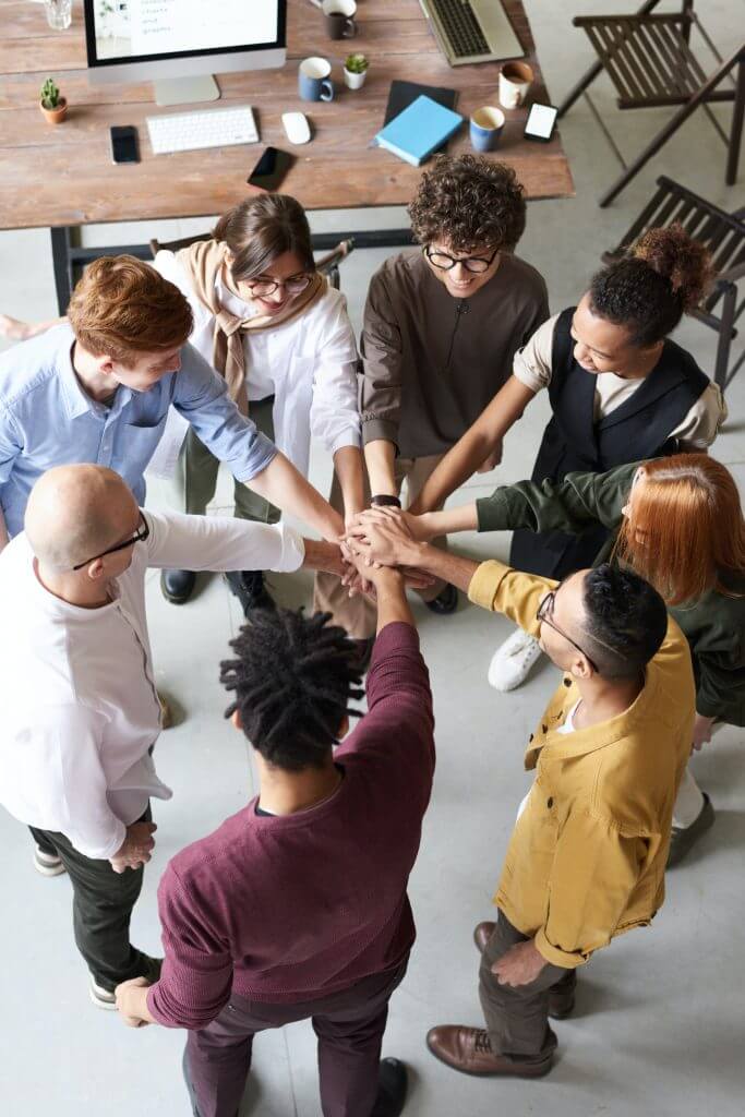 Group of young adults putting hands together in teamwork